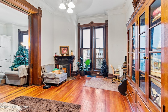 sitting room with hardwood / wood-style floors and ornamental molding