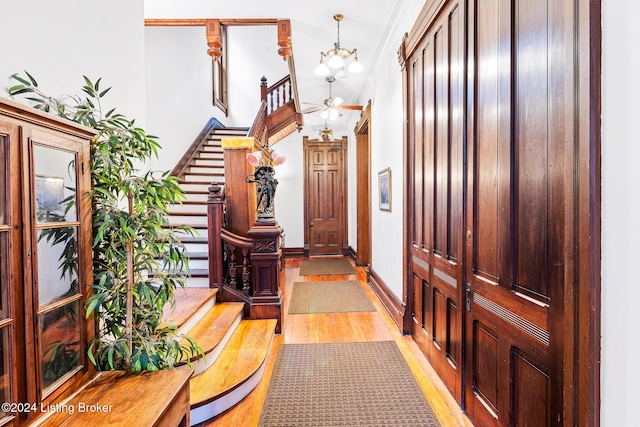 interior space featuring crown molding, light hardwood / wood-style flooring, and ceiling fan with notable chandelier