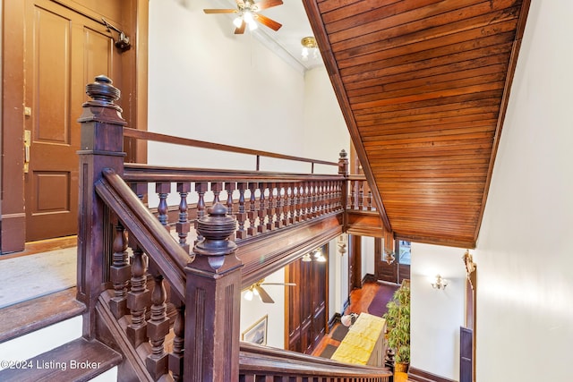 staircase featuring hardwood / wood-style flooring, crown molding, ceiling fan, and wooden ceiling