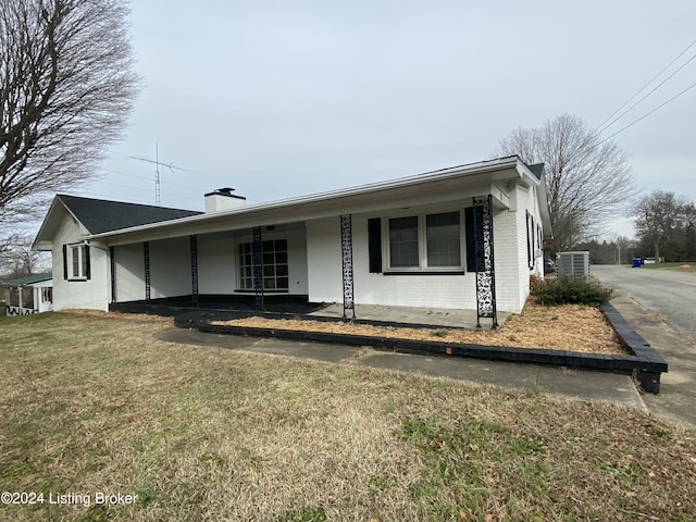 ranch-style home with a porch, a front lawn, and central air condition unit