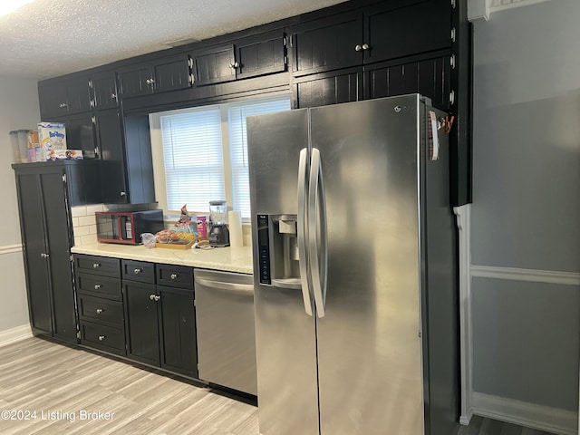 kitchen with tasteful backsplash, light hardwood / wood-style floors, a textured ceiling, and appliances with stainless steel finishes