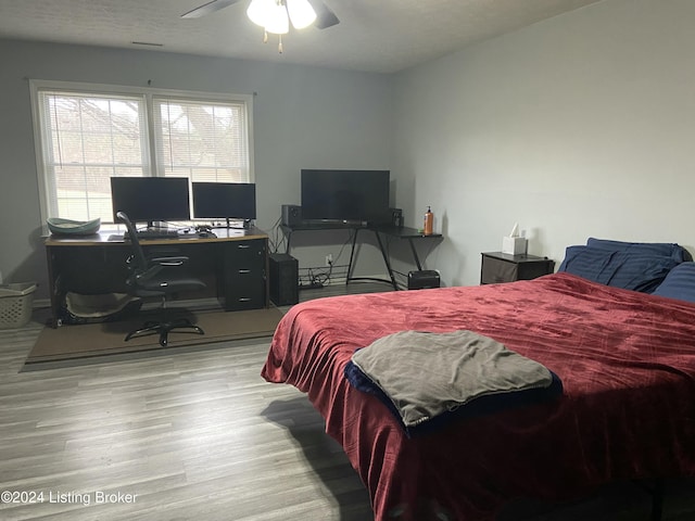 bedroom featuring ceiling fan, light hardwood / wood-style floors, and a textured ceiling