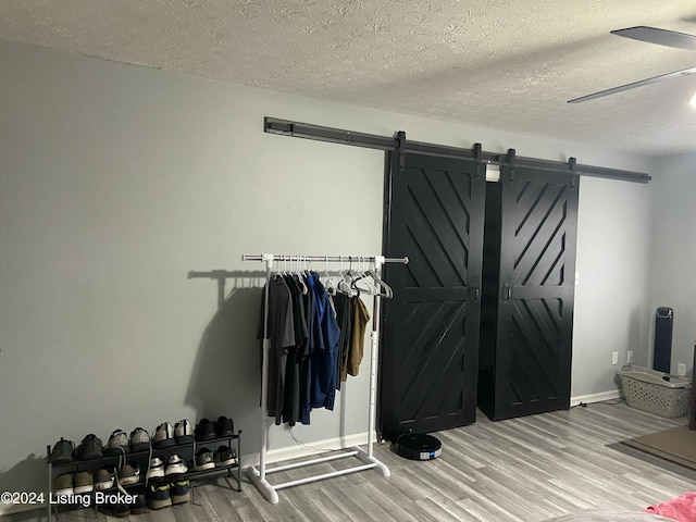 spacious closet with a barn door, hardwood / wood-style flooring, and ceiling fan