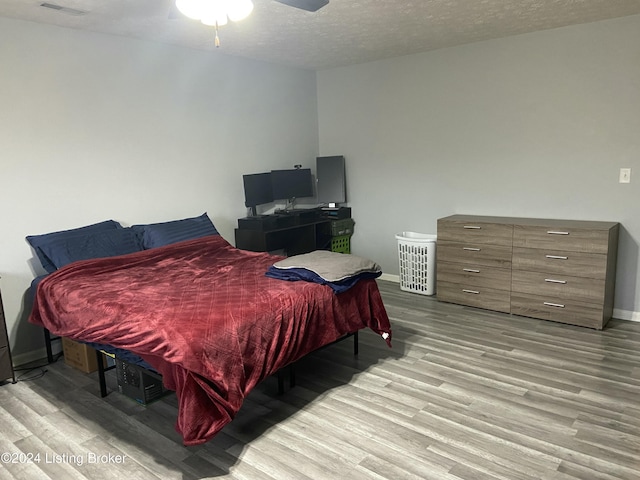 bedroom featuring ceiling fan, light hardwood / wood-style flooring, and a textured ceiling