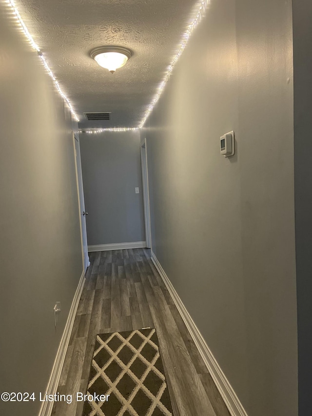 hall with dark hardwood / wood-style flooring and a textured ceiling