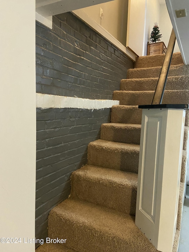 staircase featuring brick wall