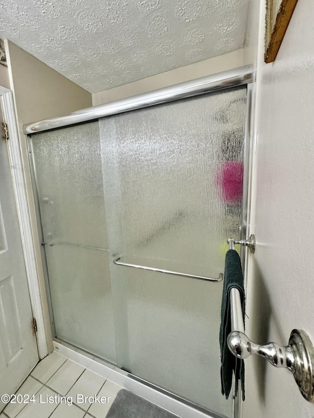 bathroom with tile patterned floors, walk in shower, and a textured ceiling