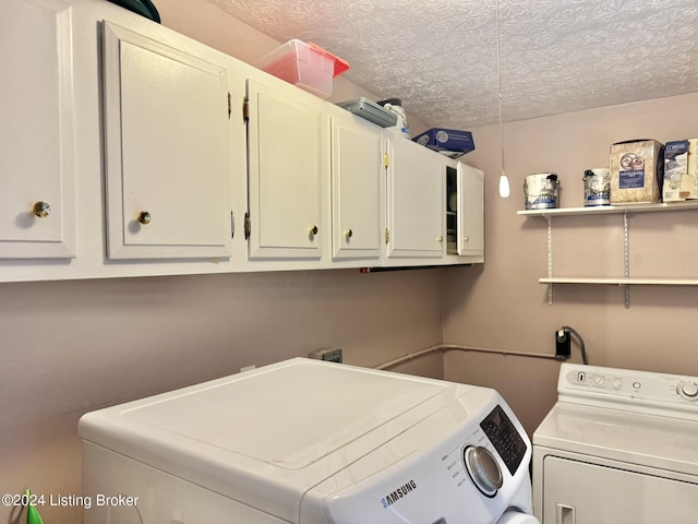 clothes washing area featuring washing machine and clothes dryer, cabinets, and a textured ceiling