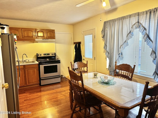 dining area featuring a textured ceiling, hardwood / wood-style flooring, ceiling fan, and sink