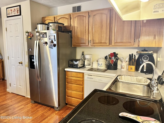 kitchen with stainless steel refrigerator with ice dispenser, light wood-type flooring, a textured ceiling, white dishwasher, and ventilation hood