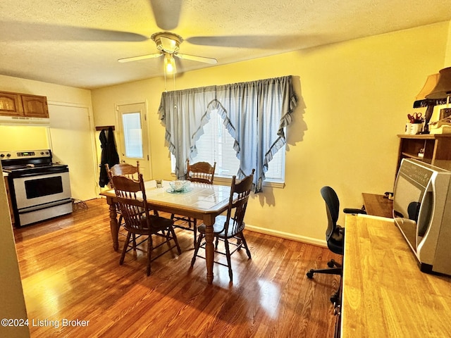 dining space with a textured ceiling, light wood-type flooring, and ceiling fan