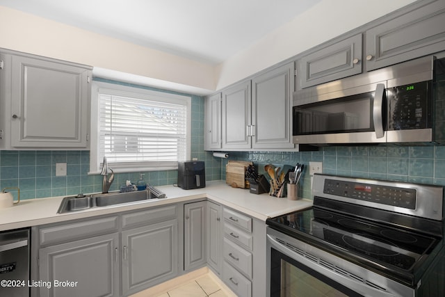 kitchen featuring decorative backsplash, appliances with stainless steel finishes, gray cabinetry, and sink