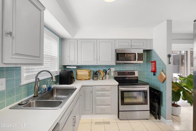 kitchen featuring decorative backsplash, light tile patterned flooring, sink, and appliances with stainless steel finishes