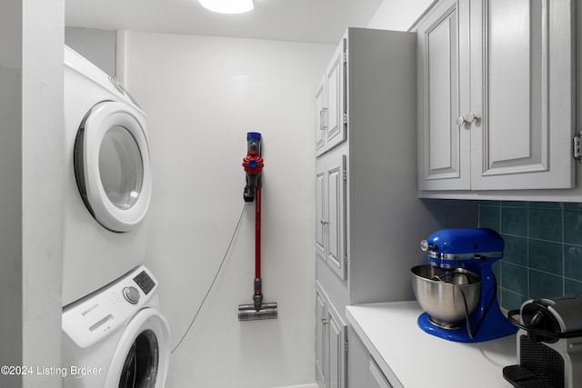 laundry area featuring cabinets and stacked washer and clothes dryer