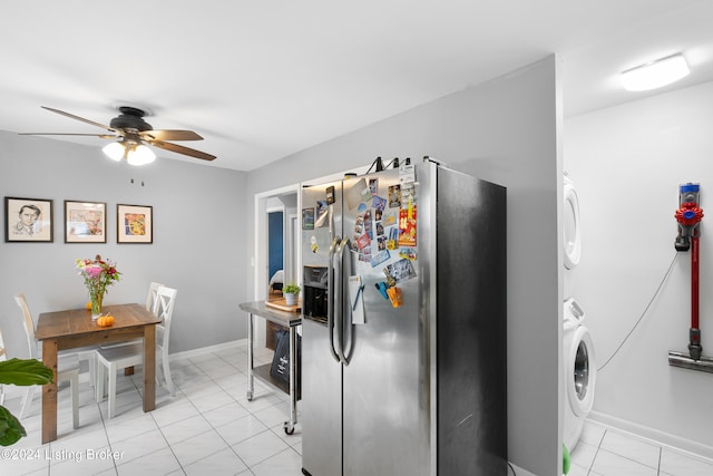 kitchen featuring stainless steel fridge with ice dispenser, ceiling fan, stacked washer / dryer, and light tile patterned flooring