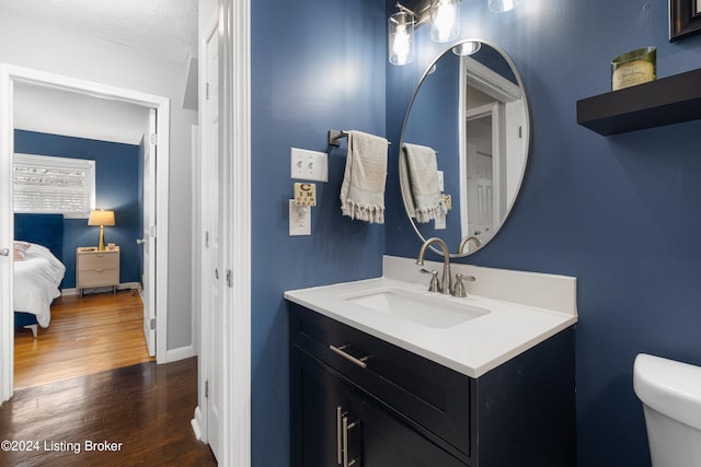 bathroom with hardwood / wood-style floors, vanity, a textured ceiling, and toilet