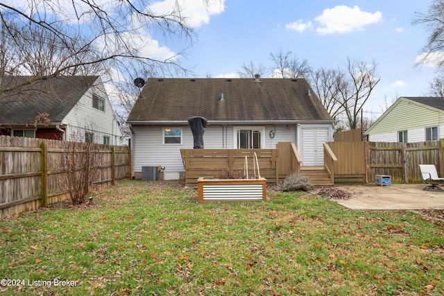 rear view of property featuring a deck, a patio area, and a lawn