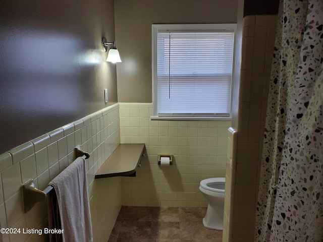 bathroom with tile patterned floors, toilet, tile walls, and walk in shower