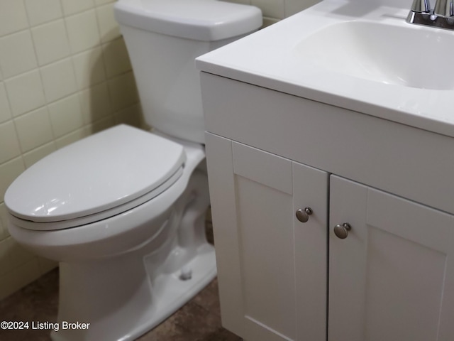 bathroom with vanity, toilet, and tile walls