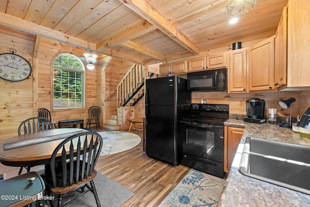 kitchen featuring light brown cabinetry, light wood-type flooring, wood ceiling, wooden walls, and black appliances