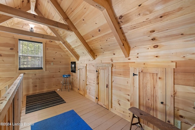 additional living space featuring vaulted ceiling with beams, wooden walls, wooden ceiling, and light wood-type flooring