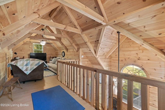 interior space featuring lofted ceiling with beams, light wood-type flooring, wooden walls, and wooden ceiling