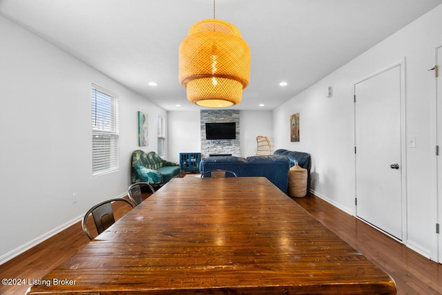 dining space featuring a stone fireplace and dark hardwood / wood-style floors