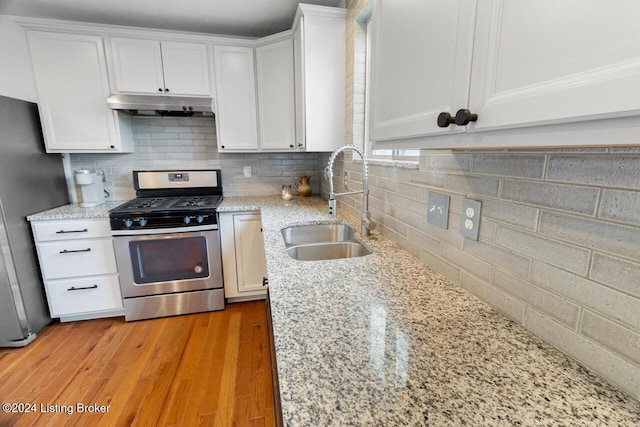 kitchen with white cabinetry, sink, light stone counters, backsplash, and appliances with stainless steel finishes