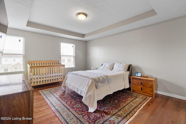 bedroom featuring a tray ceiling and dark hardwood / wood-style floors