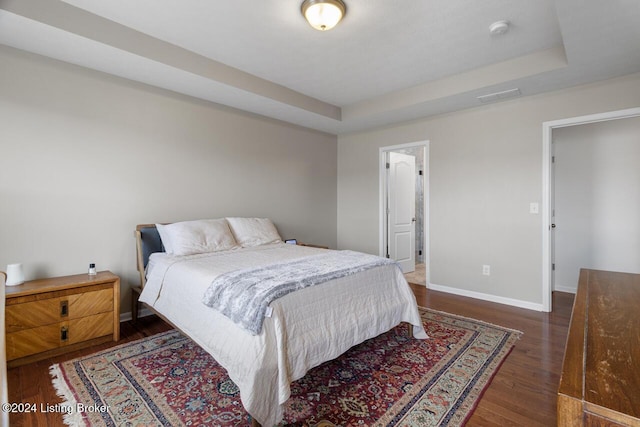 bedroom featuring a raised ceiling and dark wood-type flooring