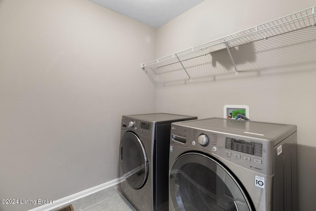 washroom with independent washer and dryer and light tile patterned floors