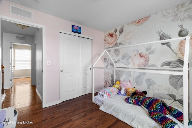 bedroom with dark hardwood / wood-style flooring and a closet