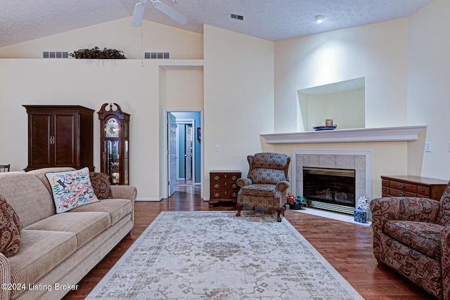 living room featuring a tile fireplace, a textured ceiling, lofted ceiling with beams, and ceiling fan