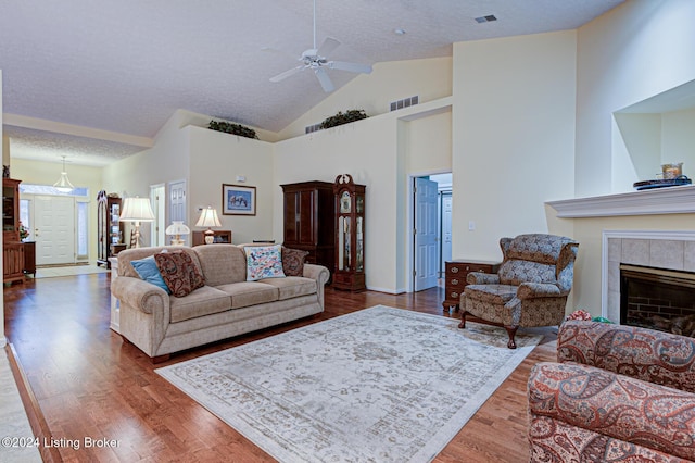 living room featuring hardwood / wood-style flooring, a fireplace, ceiling fan, and a textured ceiling