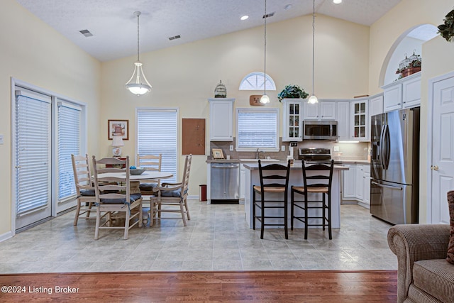 dining space with light hardwood / wood-style flooring, high vaulted ceiling, a textured ceiling, and sink