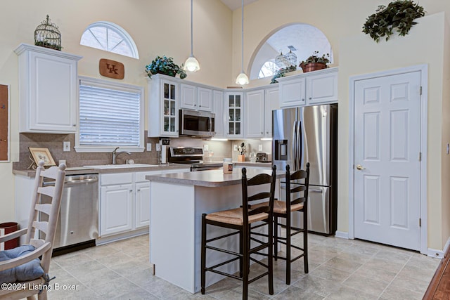 kitchen featuring decorative backsplash, white cabinetry, hanging light fixtures, and appliances with stainless steel finishes