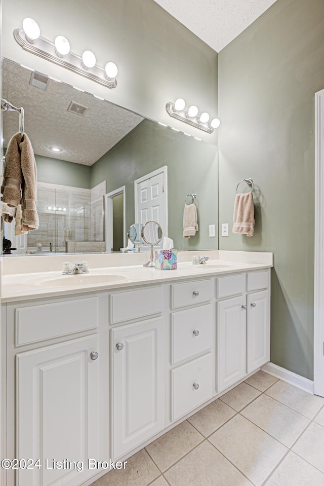 bathroom with tile patterned flooring, a textured ceiling, vanity, and an enclosed shower