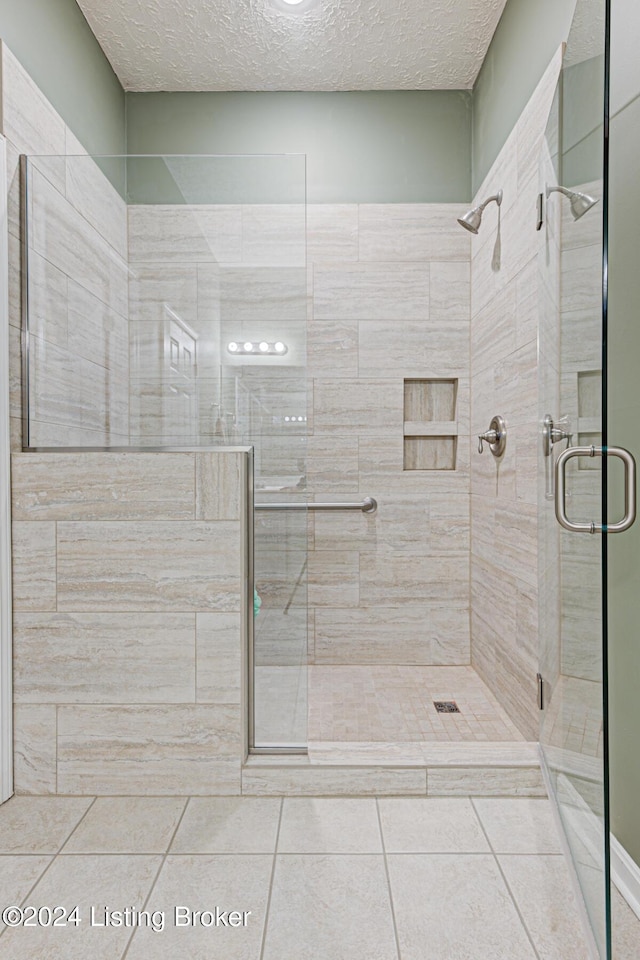 bathroom featuring a textured ceiling, tile patterned floors, and a shower with shower door