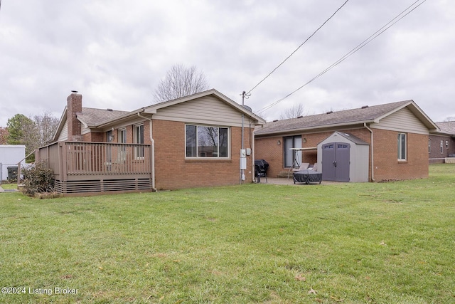 rear view of house featuring a wooden deck, a yard, and a shed