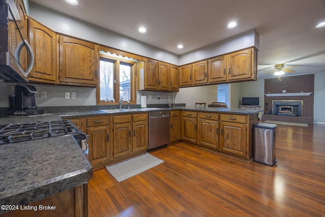 kitchen with sink, dark wood-type flooring, kitchen peninsula, and appliances with stainless steel finishes