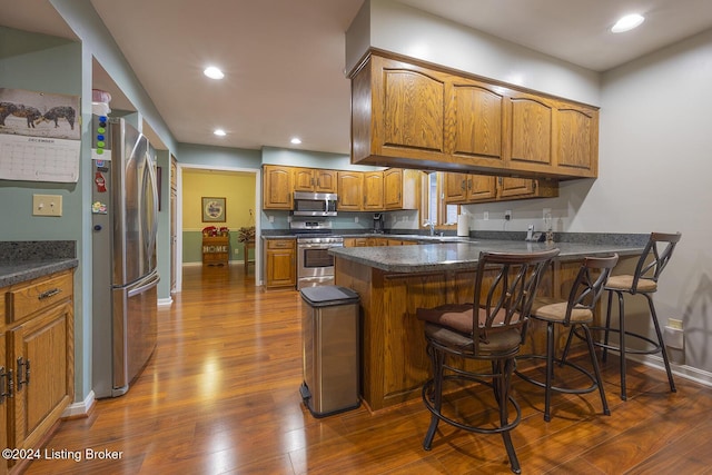 kitchen featuring sink, dark wood-type flooring, a breakfast bar, stainless steel appliances, and kitchen peninsula