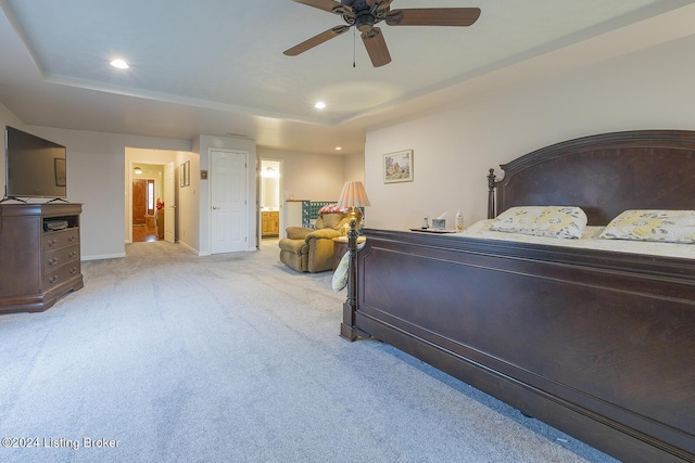 bedroom with ceiling fan, light colored carpet, and ensuite bath