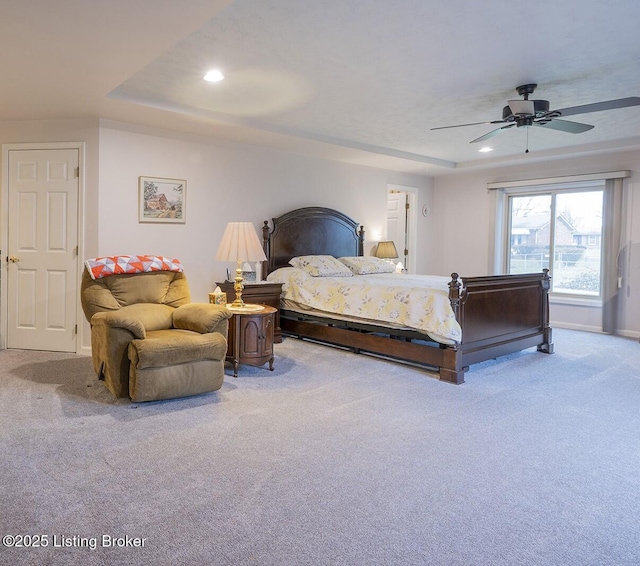 carpeted bedroom featuring ceiling fan and a raised ceiling