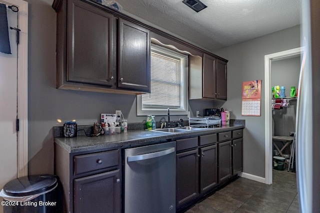 kitchen featuring appliances with stainless steel finishes, a textured ceiling, dark brown cabinetry, sink, and dark tile patterned flooring