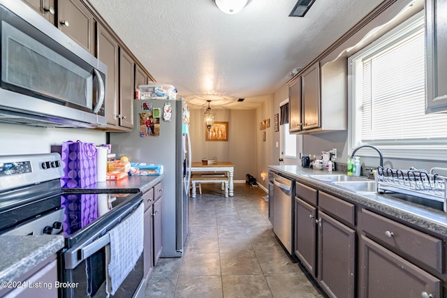 kitchen featuring a notable chandelier, sink, a textured ceiling, and appliances with stainless steel finishes