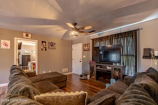 living room featuring ceiling fan, dark wood-type flooring, and a textured ceiling