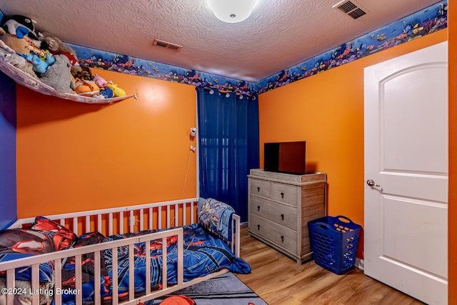 bedroom with hardwood / wood-style floors and a textured ceiling