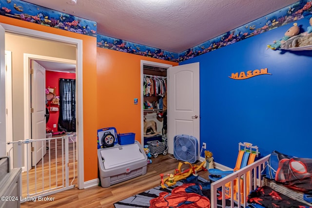 bedroom with hardwood / wood-style flooring, a textured ceiling, and a closet