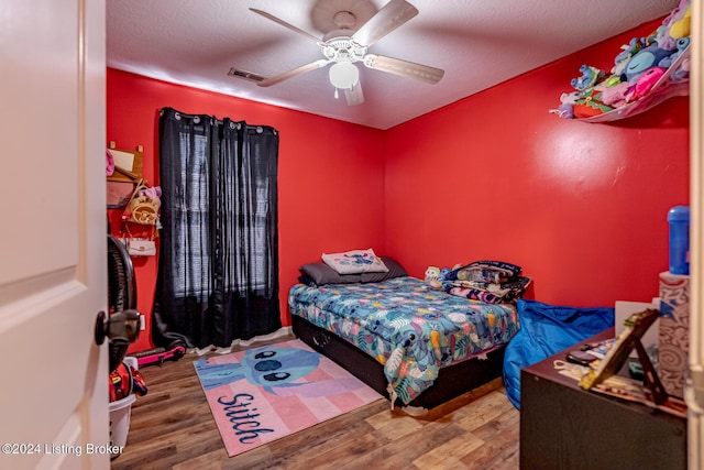 bedroom with ceiling fan, hardwood / wood-style floors, and a textured ceiling