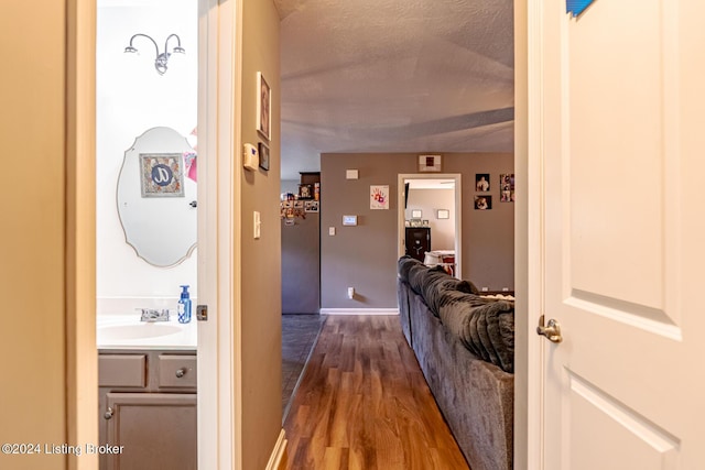 corridor featuring a textured ceiling, hardwood / wood-style flooring, and sink